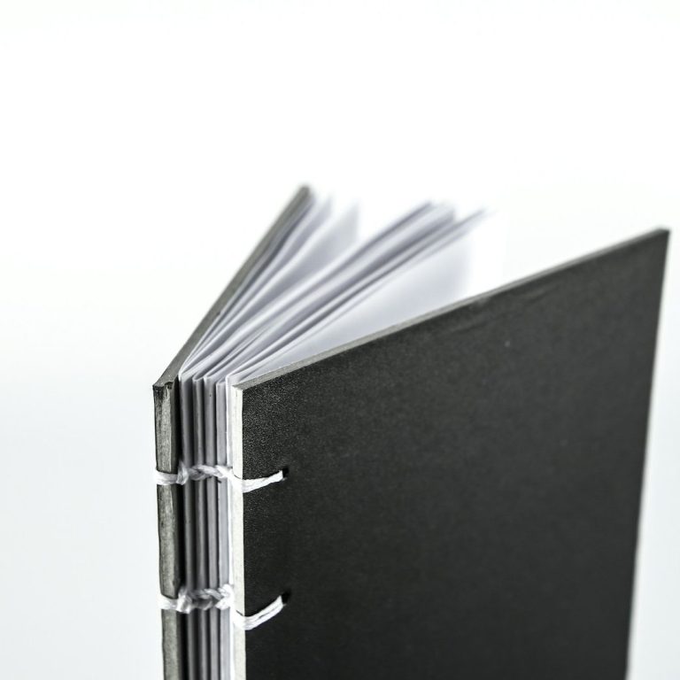 Woman holding a mug, sitting on a sofa with a laptop and plants in a sunny room.